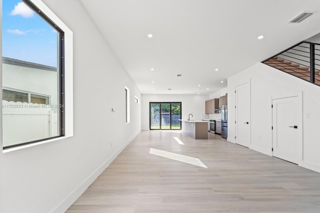 unfurnished living room with sink and light hardwood / wood-style floors