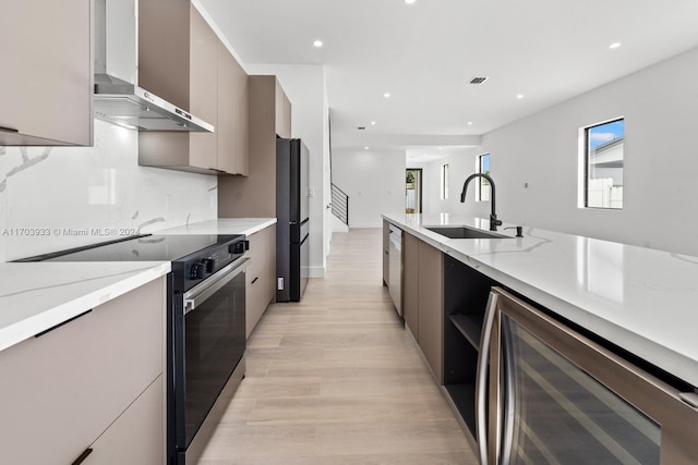 kitchen with stainless steel appliances, sink, wall chimney range hood, light hardwood / wood-style floors, and wine cooler