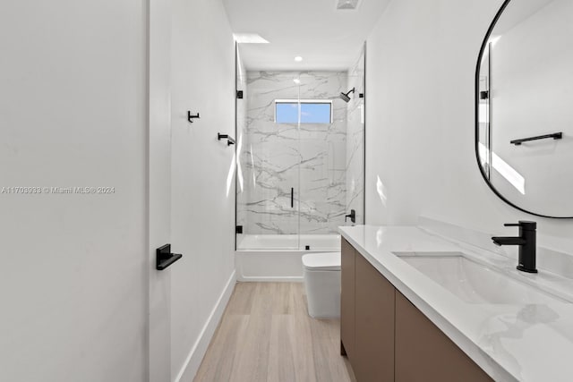 full bathroom featuring hardwood / wood-style flooring, vanity, toilet, and shower / bath combination with glass door