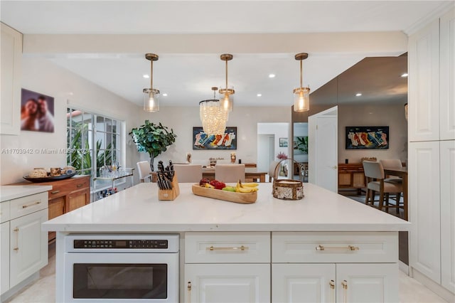 kitchen featuring a center island, white cabinetry, hanging light fixtures, and white oven