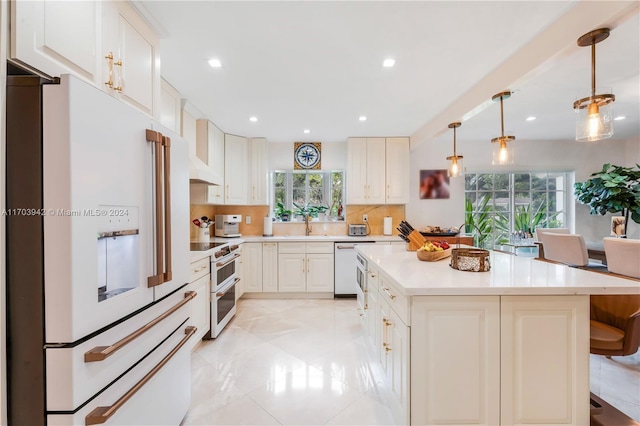 kitchen with backsplash, white appliances, decorative light fixtures, white cabinetry, and a kitchen island