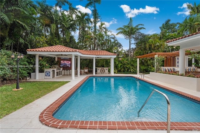 view of swimming pool featuring a gazebo, a patio area, a yard, and exterior kitchen