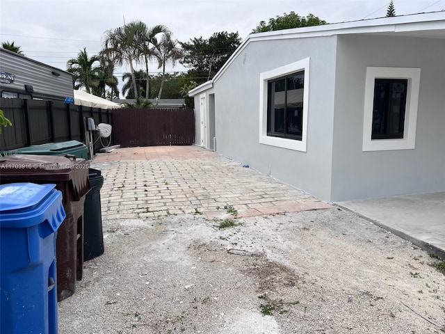 view of side of home featuring fence, a patio, and stucco siding