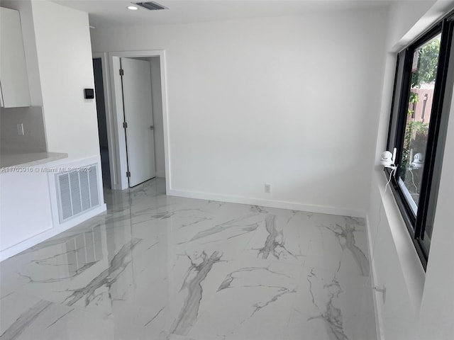 empty room featuring marble finish floor, baseboards, and visible vents