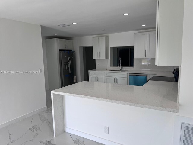 kitchen featuring dishwashing machine, a peninsula, marble finish floor, refrigerator with ice dispenser, and a sink