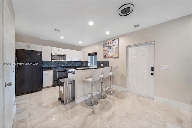 kitchen featuring a kitchen breakfast bar, backsplash, kitchen peninsula, white cabinets, and appliances with stainless steel finishes