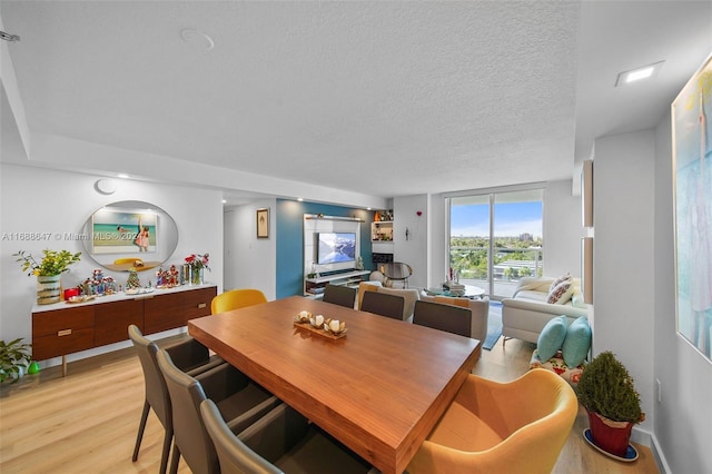 dining area with a textured ceiling and light hardwood / wood-style flooring