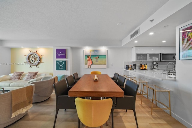 dining room with a textured ceiling, light hardwood / wood-style floors, and sink