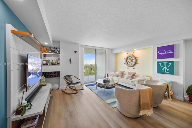 living room with a textured ceiling, light hardwood / wood-style floors, and expansive windows