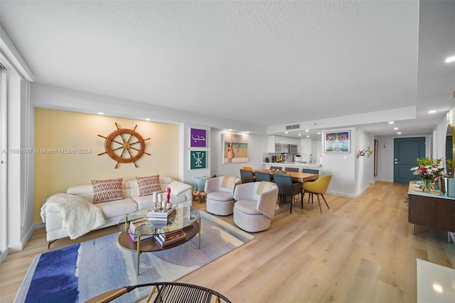 living room featuring light hardwood / wood-style flooring and a textured ceiling