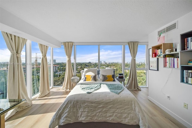 bedroom with a textured ceiling, multiple windows, and light hardwood / wood-style flooring