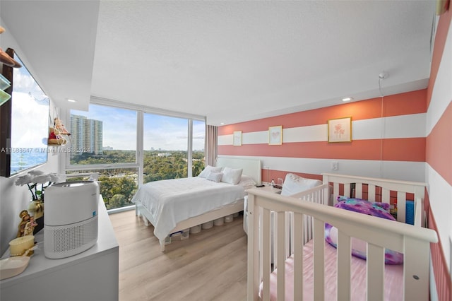 bedroom with expansive windows and light hardwood / wood-style flooring