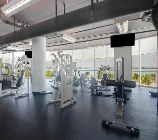 gym with floor to ceiling windows and a healthy amount of sunlight