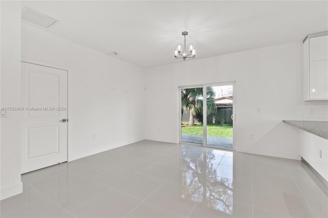 unfurnished room with light tile patterned flooring and a chandelier