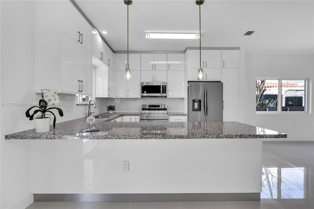 kitchen featuring pendant lighting, white cabinets, kitchen peninsula, and stainless steel appliances