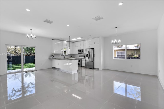 kitchen featuring white cabinets, stainless steel appliances, decorative light fixtures, and a notable chandelier