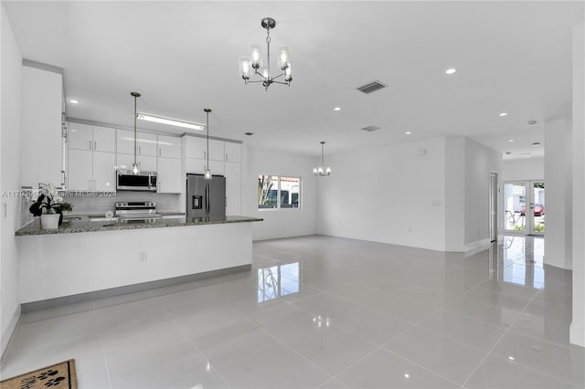 kitchen featuring dark stone countertops, white cabinetry, hanging light fixtures, and appliances with stainless steel finishes