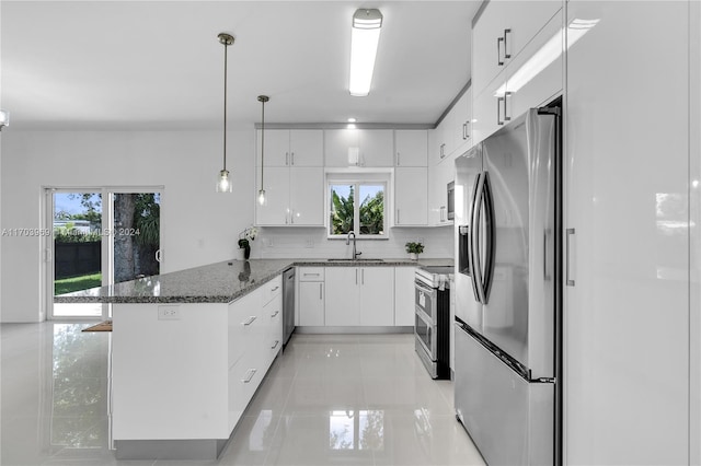 kitchen with pendant lighting, dark stone countertops, white cabinetry, kitchen peninsula, and stainless steel appliances