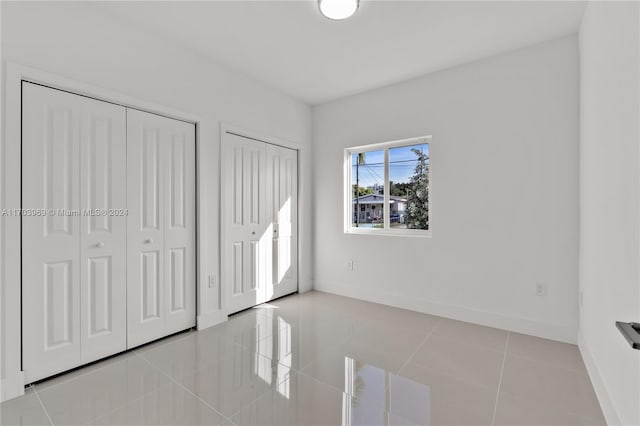 unfurnished bedroom featuring multiple closets and light tile patterned flooring