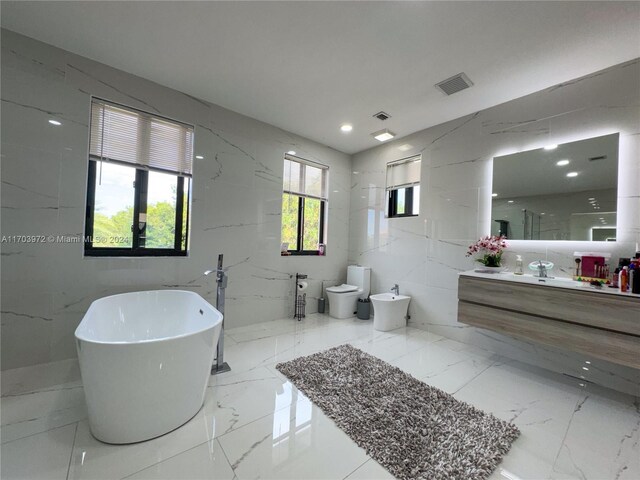 bathroom with vanity, tile walls, a bidet, toilet, and a tub