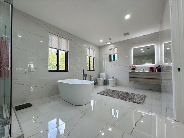 bathroom featuring a washtub, vanity, a bidet, tile walls, and toilet