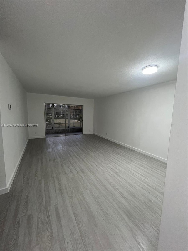 unfurnished living room with wood-type flooring and a textured ceiling