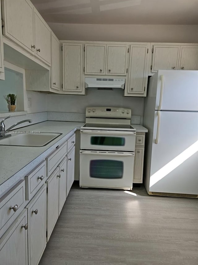 kitchen with white appliances, light hardwood / wood-style floors, and sink