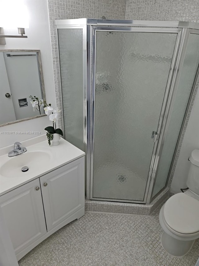 bathroom with tile patterned flooring, vanity, toilet, and a shower with shower door