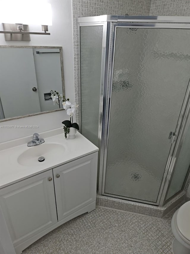 bathroom featuring tile patterned floors, vanity, toilet, and walk in shower