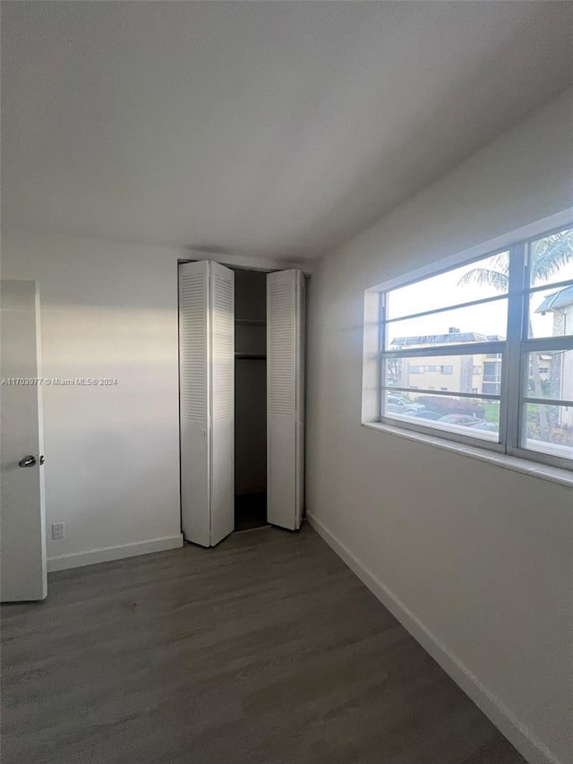 unfurnished bedroom featuring multiple windows and dark wood-type flooring