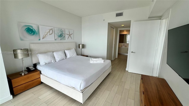 bedroom featuring connected bathroom and light hardwood / wood-style floors