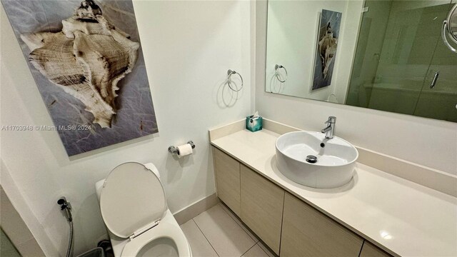 bathroom with an enclosed shower, vanity, toilet, and tile patterned floors