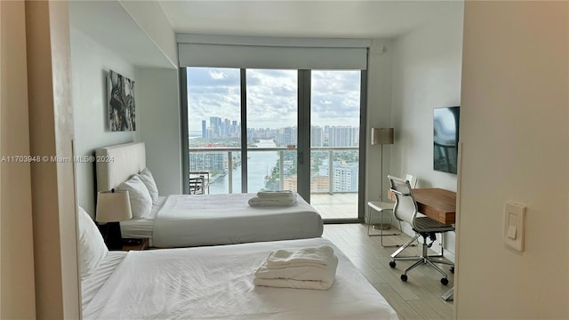 bedroom featuring access to exterior, a water view, and light hardwood / wood-style flooring