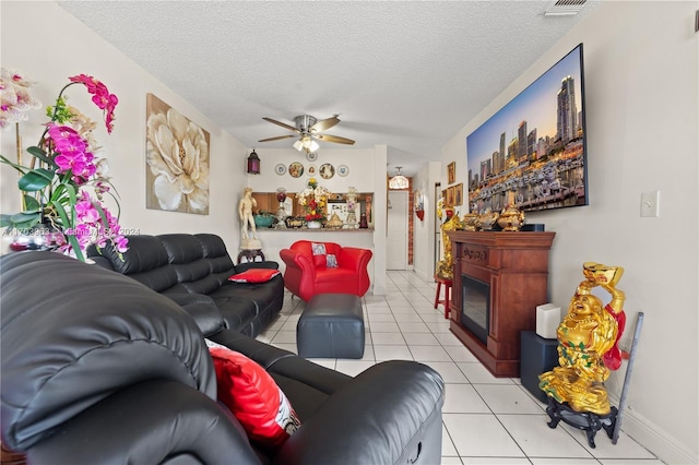 tiled living room with ceiling fan and a textured ceiling