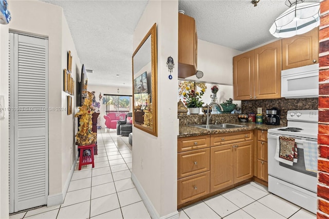 kitchen featuring a textured ceiling, white appliances, sink, and light tile patterned floors