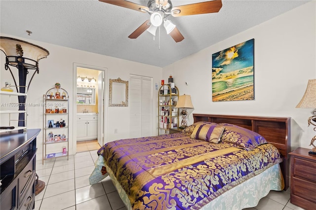 tiled bedroom featuring a closet, a textured ceiling, ensuite bathroom, and ceiling fan