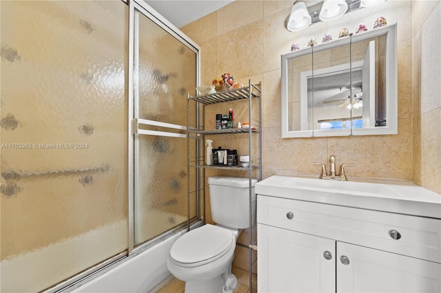 full bathroom with ceiling fan, vanity, enclosed tub / shower combo, and tile walls