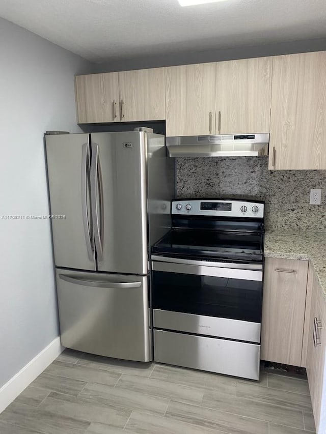 kitchen with light brown cabinets, light stone counters, and appliances with stainless steel finishes