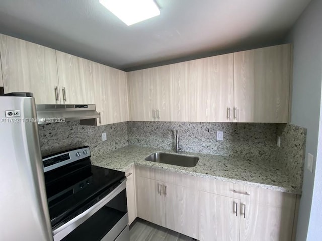 kitchen with light brown cabinetry, refrigerator, backsplash, stainless steel range with electric stovetop, and sink