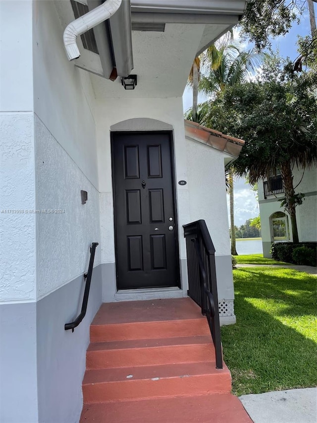 property entrance with a lawn and a water view