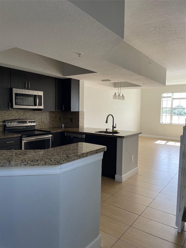 kitchen featuring a textured ceiling, decorative light fixtures, backsplash, and stainless steel appliances