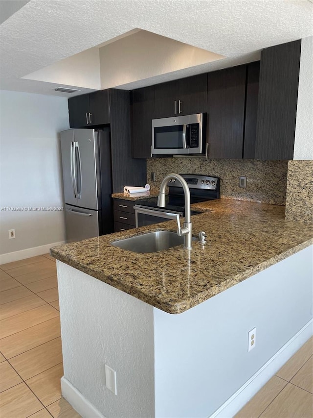 kitchen with kitchen peninsula, a textured ceiling, backsplash, and stainless steel appliances