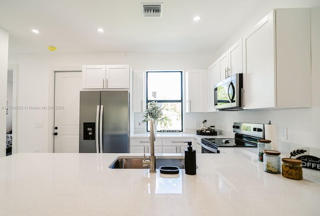 kitchen featuring light stone countertops, sink, white cabinets, and stainless steel appliances