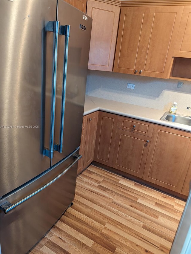 kitchen featuring tasteful backsplash, sink, high end refrigerator, and light hardwood / wood-style floors