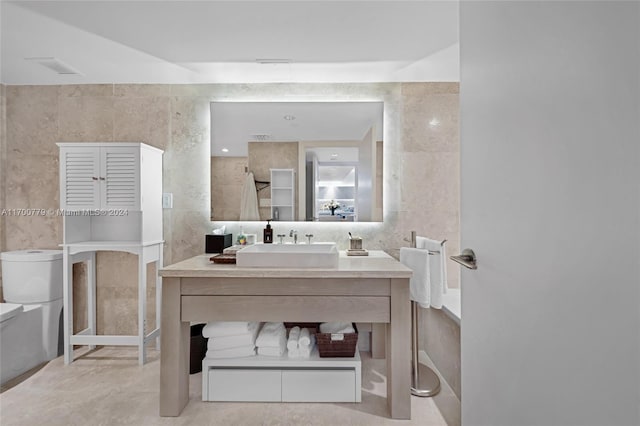 bathroom with vanity, toilet, and tile walls