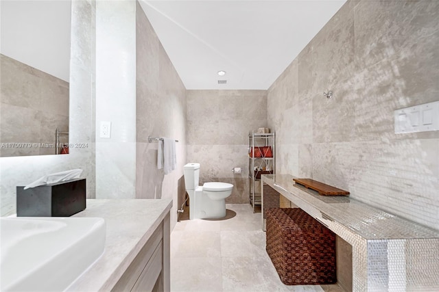 bathroom with sink, tile patterned flooring, tile walls, and toilet