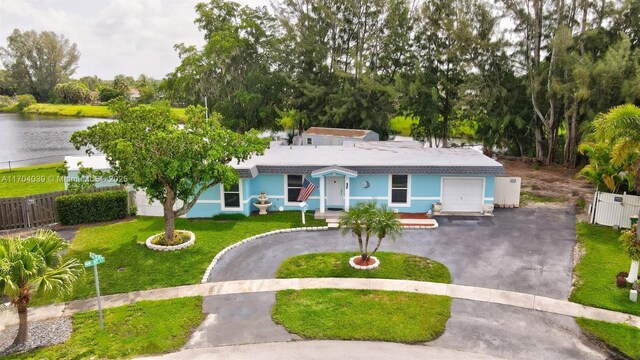 single story home with a garage, a water view, and a front lawn