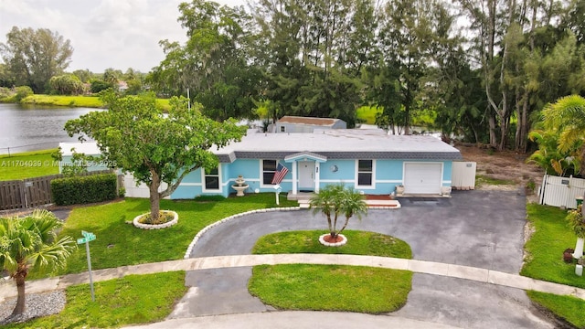 ranch-style home with driveway, a front lawn, a water view, and fence