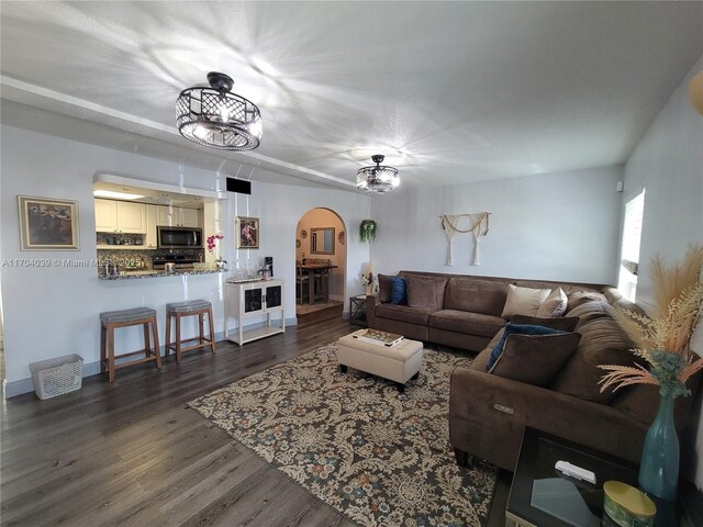 living room featuring a notable chandelier and dark wood-type flooring