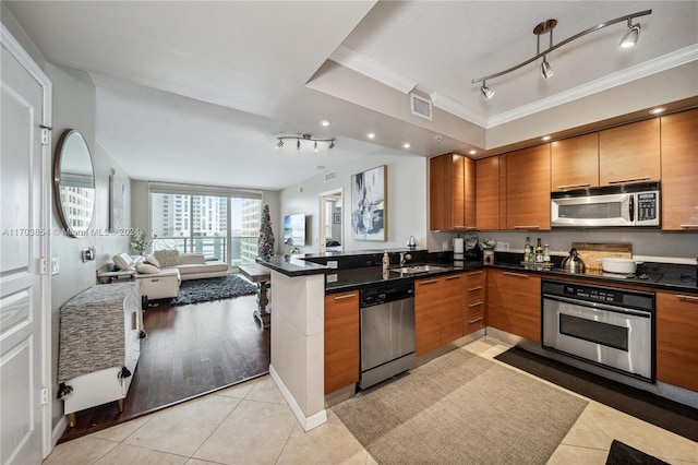 kitchen featuring kitchen peninsula, stainless steel appliances, crown molding, sink, and light tile patterned floors